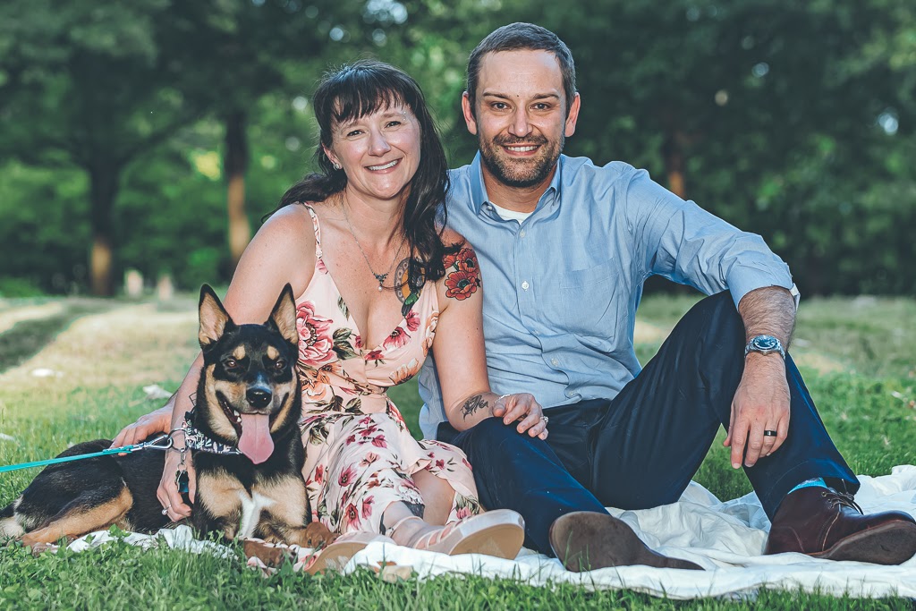 family photo with a women, man and dog sitting in grass